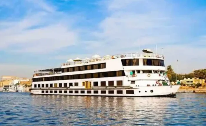 A beautiful sunset view over the Nile River with a classic cruise ship sailing between Aswan and Luxor.
