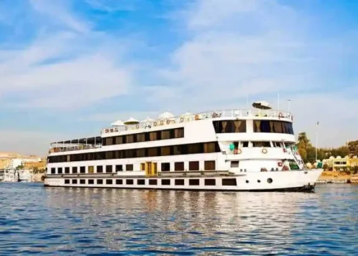 A beautiful sunset view over the Nile River with a classic cruise ship sailing between Aswan and Luxor.