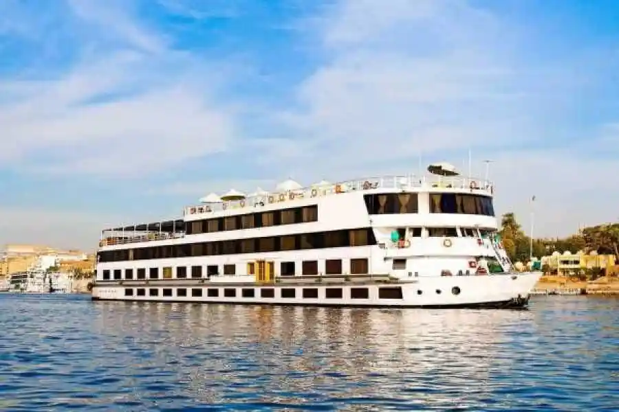 A beautiful sunset view over the Nile River with a classic cruise ship sailing between Aswan and Luxor.